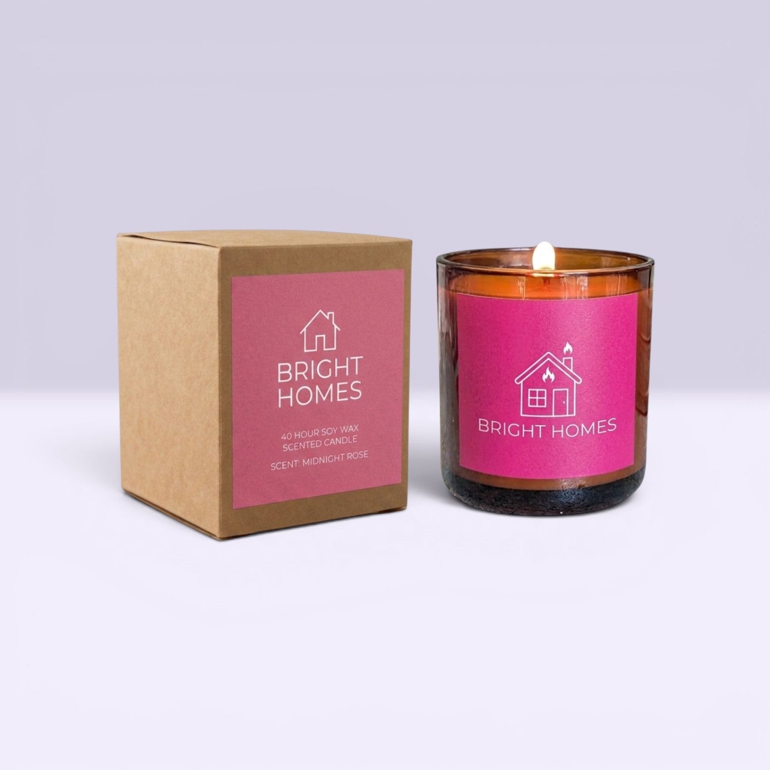 A lit amber glass scented candle next to its brown kraft paper packaging box, both featuring a bright pink label with the brand name 'BRIGHT HOMES' and a house icon.