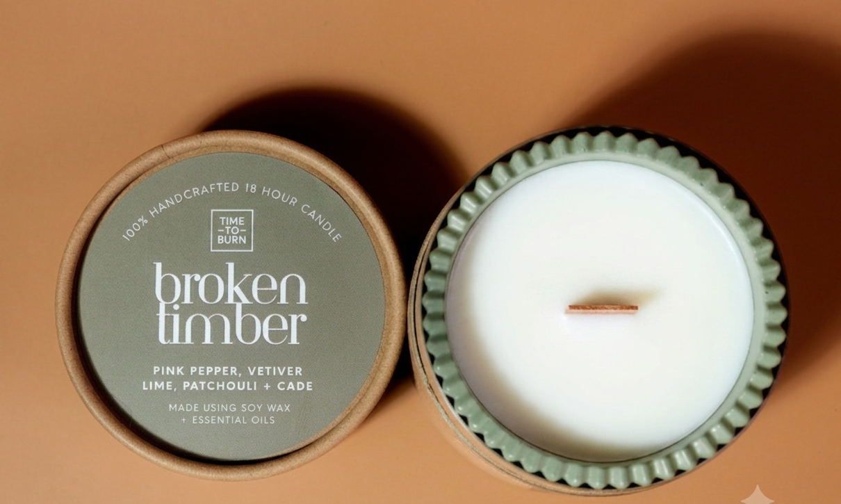 'broken timber' scented soy wax candle with wooden wick. displaying its olive green lid with white text, and the other is open, showing the white soy wax inside a textured sage green handmadejesmonite candle jar with a single wick.